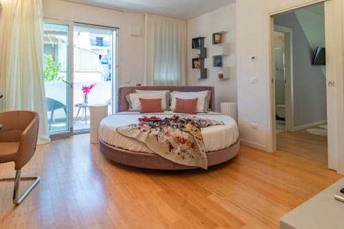 Modern round bed in Pescara INN Family Connecting Suite with wooden floors, balcony access, and contemporary furnishings