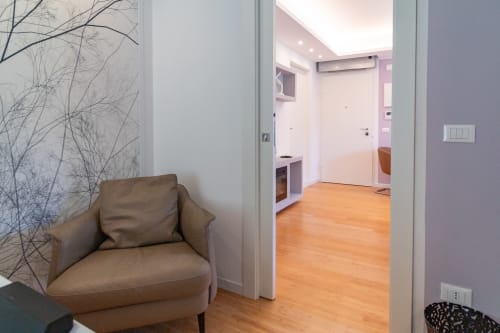 Pescara INN Family Connecting Suite entryway with tan armchair, wooden floors, and modern hallway leading to bedroom area