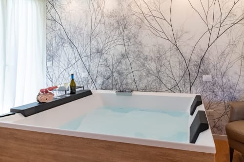 Modern bathtub with turquoise water and black trim at Pescara INN's Essenza Family Suite, featuring minimalist décor and bare