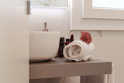 Bathroom vanity at Pescara INN with rolled towel, soap dispenser, and toiletries