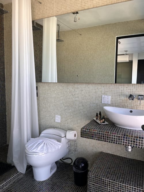 Modern bathroom with mosaic tile walls, vessel sink, and toilet at Vidasoul BnB in La Vinorama, Mexico