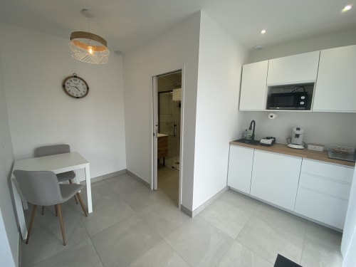Moderne Küche und Essbereich in der Wohnung La Maison Blanche, Bouguenais, mit weißen Möbeln und Esstisch