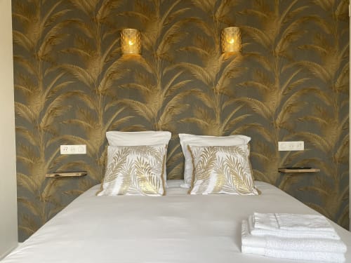 Modernes Schlafzimmer im La Maison Blanche mit goldenem Palmblatt-Tapete, weißer Bettwäsche und Wandleuchten