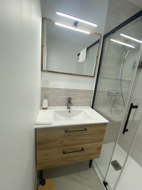 Modernes Badezimmer im Apartment La Maison Blanche mit Holzwaschbecken, beleuchtetem Spiegel und geschlossener Dusche in Bouguenais