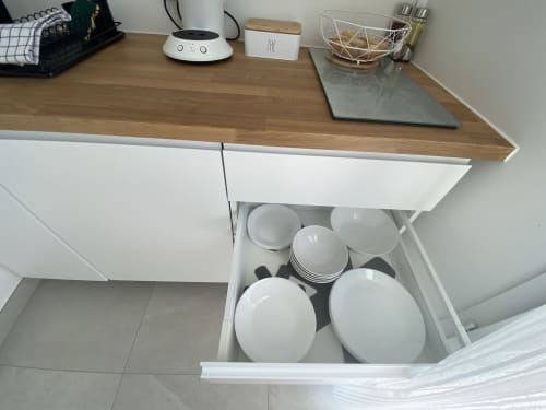 Offene Küchenschublade mit weißem Tafelgeschirr und Besteck in der Wohnung La Maison Blanche in Bouguenais