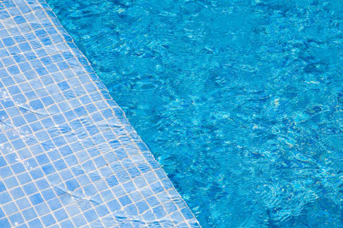 Acqua cristallina della piscina con bordo piastrellato al Corte Baruzzo Relais di Volta Mantovana