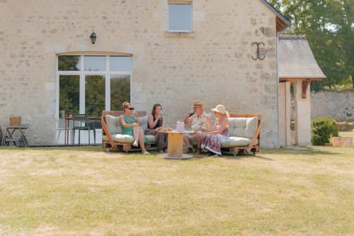 Quatre convives savourant des boissons sur des transats en bois autour d'un foyer à Le Hameau de Céline B&B à Landes-le-Gaulois, France