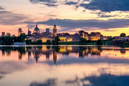 Lo skyline di Mantova al tramonto riflesso nelle acque calme, con la cattedrale storica e gli edifici vicino al Relais Corte Baruzzo