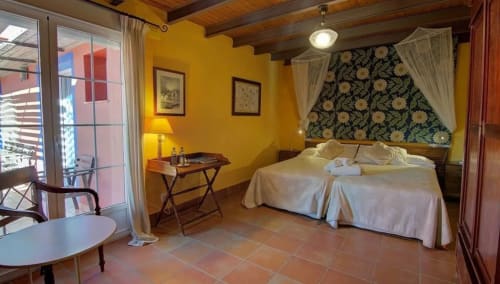 Bright yellow bedroom at Casa Gallinera with double bed, wooden beams, and terracotta floors in Alicante