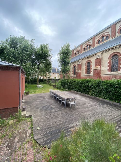 Terrasse en bois avec table de salle à manger du Gîte Presbytère de l'Hidden Bay Hotel à Cayeux-sur-Mer, adjacent à l'église en brique