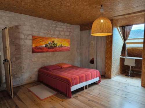 Chambre Basiniak à la Madiana 89 BnB à Bellechaume avec literie rayée rouge, luminaire suspendu tressé et vue sur le jardin