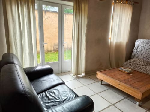 Chambre avec vue sur le jardin à Madiana 89 B&B à Bellechaume, fauteuil cuir noir, lit en bois et accès à la terrasse