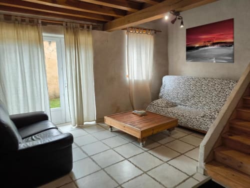 Séjour cosy à la Maison Basiniak Madiana 89 de Bellechaume avec canapé, fauteuil cuir, table basse en bois et vue sur le jardin