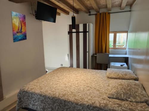 Chambre Coco au B&B Madiana 89 à Bellechaume : lit queen-size, poutres apparentes, TV, vue jardin et équipements modernes.