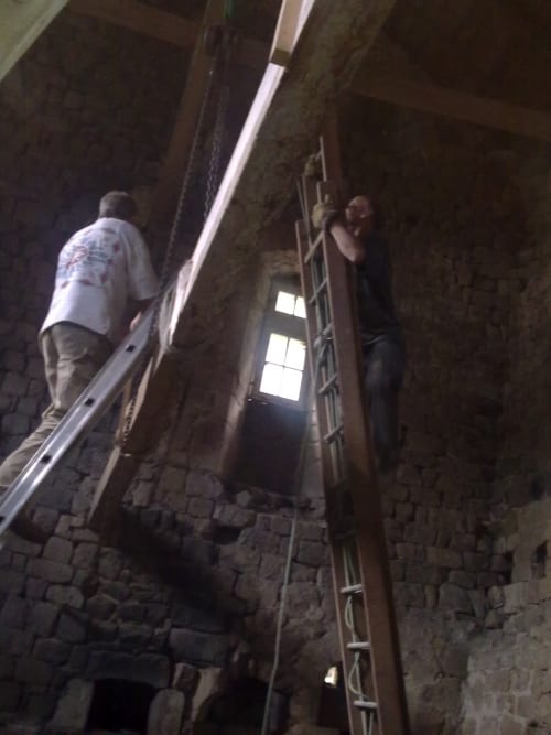 Deux ouvriers installent des gouttières métalliques sur les murs en pierre rustique du gîte Domaine De Maleval à Mars, France