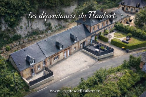 Vue aérienne du gîte Les Gites de Flaubert niché dans la verdure avec bâtisses en pierre et jardins paysagés