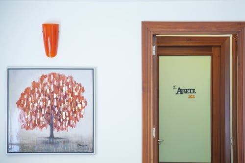 Ingresso della camera d'albergo all'Hotel Ristorante alle Querce di Castelbuono con porta in legno e decorativo dipinto d'albero su parete bianca