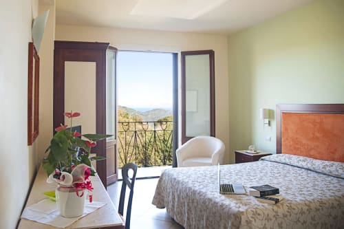 Spaziosa camera con vista montagna all'Hotel Ristorante alle Querce di Castelbuono, con balcone, letto matrimoniale e zona salotto