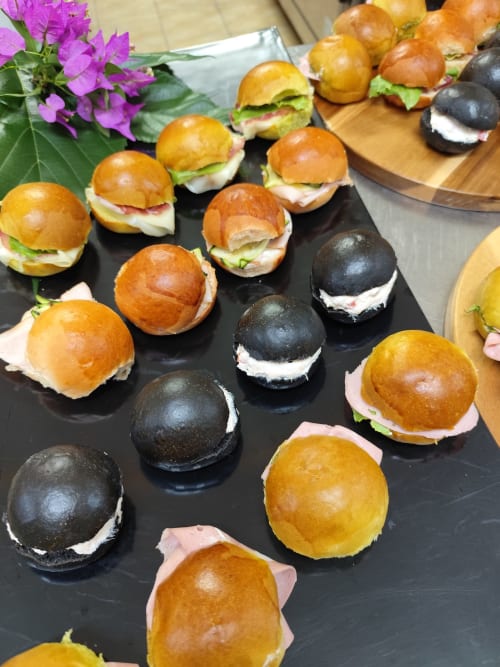 Eleganti mini slider e canapé all'Hotel Ristorante alle Querce di Castelbuono, con verdure fresche e fiori rosa