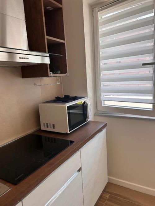 Angolo cucina moderno all'Anima Est B&B Napoli con piano cottura a induzione, microonde e finestra con veneziane a righe
