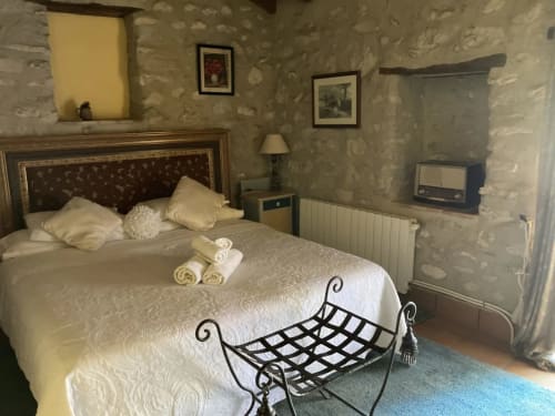 Elegant slaapkamer in boutique plattelandshotel Casa Gallinera in Alicante met wit beddengoed, decoratieve smeedijzeren bank en