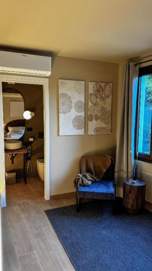 Chambre moderne de la Chambre d'Hôtes Dolceacqua avec moquette bleue, salle de bain attenante, vue sur la fenêtre et mobilier contemporain