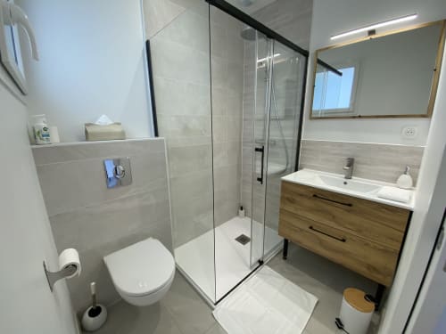 Modern bathroom in La Maison Blanche apartment with walk-in shower, wooden vanity, and white fixtures