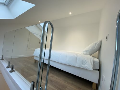 Modern loft bedroom with bed, mirror, skylight, and wooden flooring at La Maison Blanche, Bouguenais