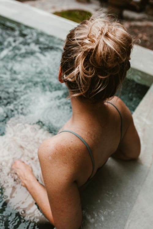 Woman in bikini enjoying outdoor hot spring pool at Talking Stones Group in Dolceacqua, Italy