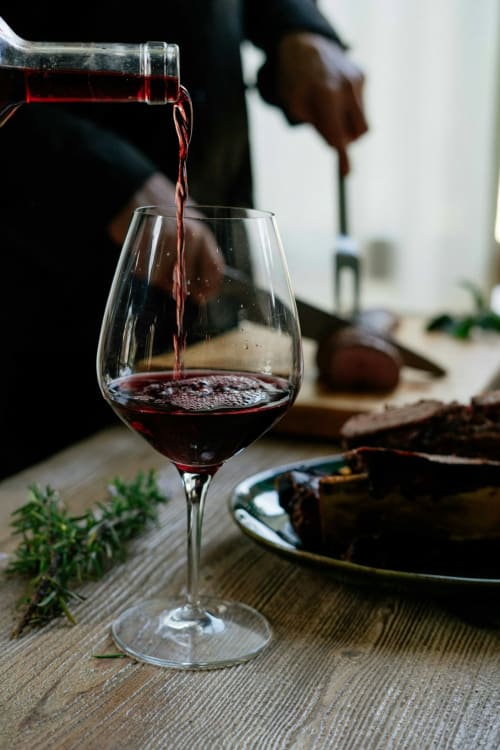 Red wine being poured into a glass at Talking Stones Group dining experience in Dolceacqua