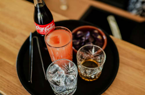 Bouteille de Coca-Cola et boissons colorées sur plateau noir à l'hôtel Lieu-dit Boulage à Marquefave, France