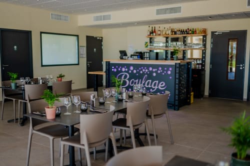 Espace événementiel moderne de l'hôtel Lieu-dit Boulage à Marquefave avec tables de salle à manger, bar et enseigne en néon violet