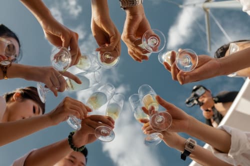 Group toasting with drinks at Talking Stones Group in Dolceacqua, Italy, celebrating together under blue sky