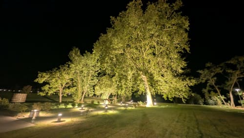 Jardin nocturne de l'hôtel Lieu-dit Boulage à Marquefave avec arbres illuminés et pelouse entretenue