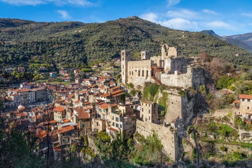 Il castello medievale e il villaggio di Dolceacqua in Italia con tetti in terracotta immersi nelle colline boschive