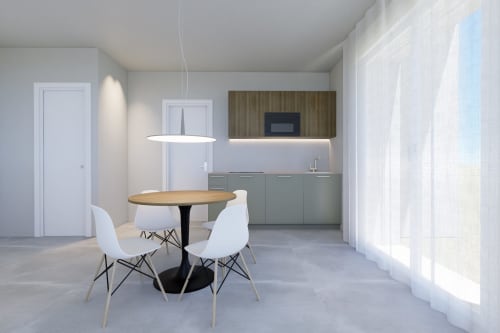 Cucina moderna e zona pranzo negli Appartamenti Riviera di Pesaro con tavolo rotondo in legno, sedie bianche e angolo cottura attrezzato