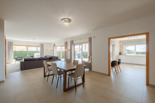 Ampla villa moderna com área de sala de jantar e estar, vista para a piscina, mesa de madeira, sofá escuro e espaçoso em Be SilverCoast