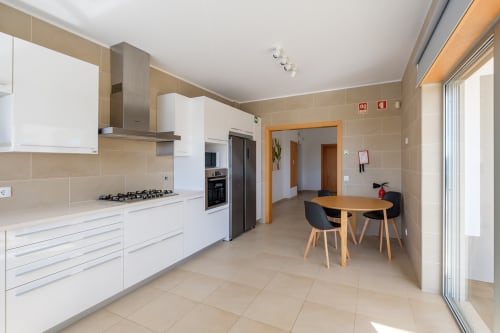Cozinha e sala de jantar moderna na Marvellous Villa em Be SilverCoast, Serra D'El Rei, com marcenaria branca e mesa de madeira