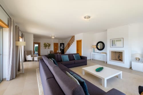 Ampla sala de estar da Marvellous Villa em Be SilverCoast com sofás escuros, lareira e escadas em Serra D'El Rei, Portugal