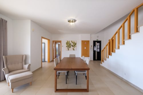 Ampla sala de jantar na Villa Marvellous do hotel Be SilverCoast, Serra D'El Rei, com mesa de madeira, cadeiras, escada e