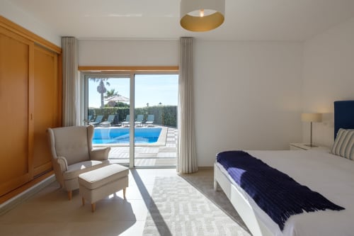 Quarto impressionante da Villa Be SilverCoast com vista para a piscina, portas-pátio privadas, área de estar em tons creme e móveis modernos