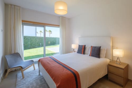 Quarto luminoso na villa Be SilverCoast com vista para o jardim, cama branca, móveis modernos e portas de correr que se abrem para a vegetação