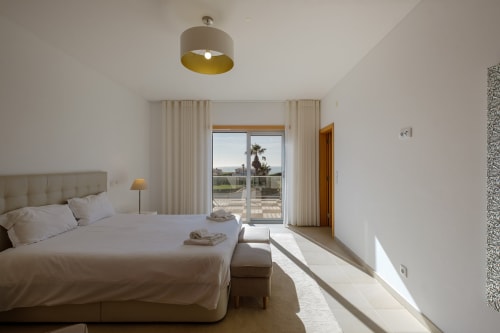 Quarto moderno e iluminado na villa Be SilverCoast com vista para piscina, roupa de cama neutra, portas de vidro para terraço, design contemporâneo