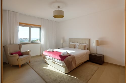 Quarto luminoso na villa Be SilverCoast com cama de casal, poltrona e vista natural para Serra D'El Rei