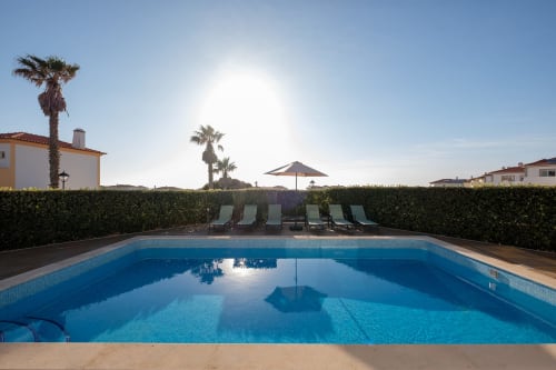 Piscina privada da villa Be SilverCoast em Serra D'El Rei com espreguiçadeiras, guarda-sol e palmeiras