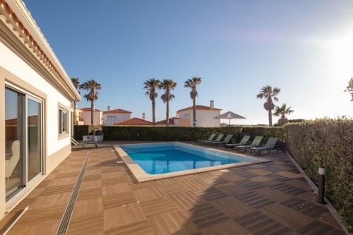 Terraço com piscina privada da villa Be SilverCoast em Serra D'El Rei, equipado com deck de madeira, espreguiçadeiras e palmeiras