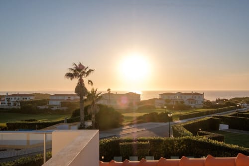 Vista do pôr do sol da villa Be SilverCoast em Serra D'El Rei com piscina, palmeiras e paisagem costeira