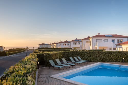 Villa SilverCoast com piscina privada, espreguiçadeiras e pátio delimitado por sebes ao anoitecer em Serra D'El Rei, Portugal