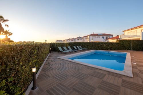 Piscina privada ao pôr do sol, villa Be SilverCoast em Serra D'El Rei com espreguiçadeiras e cerca viva de privacidade