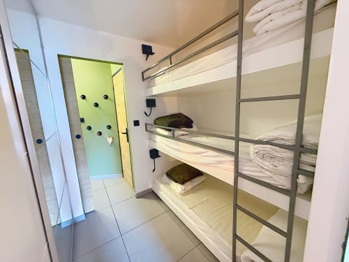 Chambre lumineuse du gîte avec lits superposés trois étages et salle de bain moderne aux Tanières de Montgenèvre